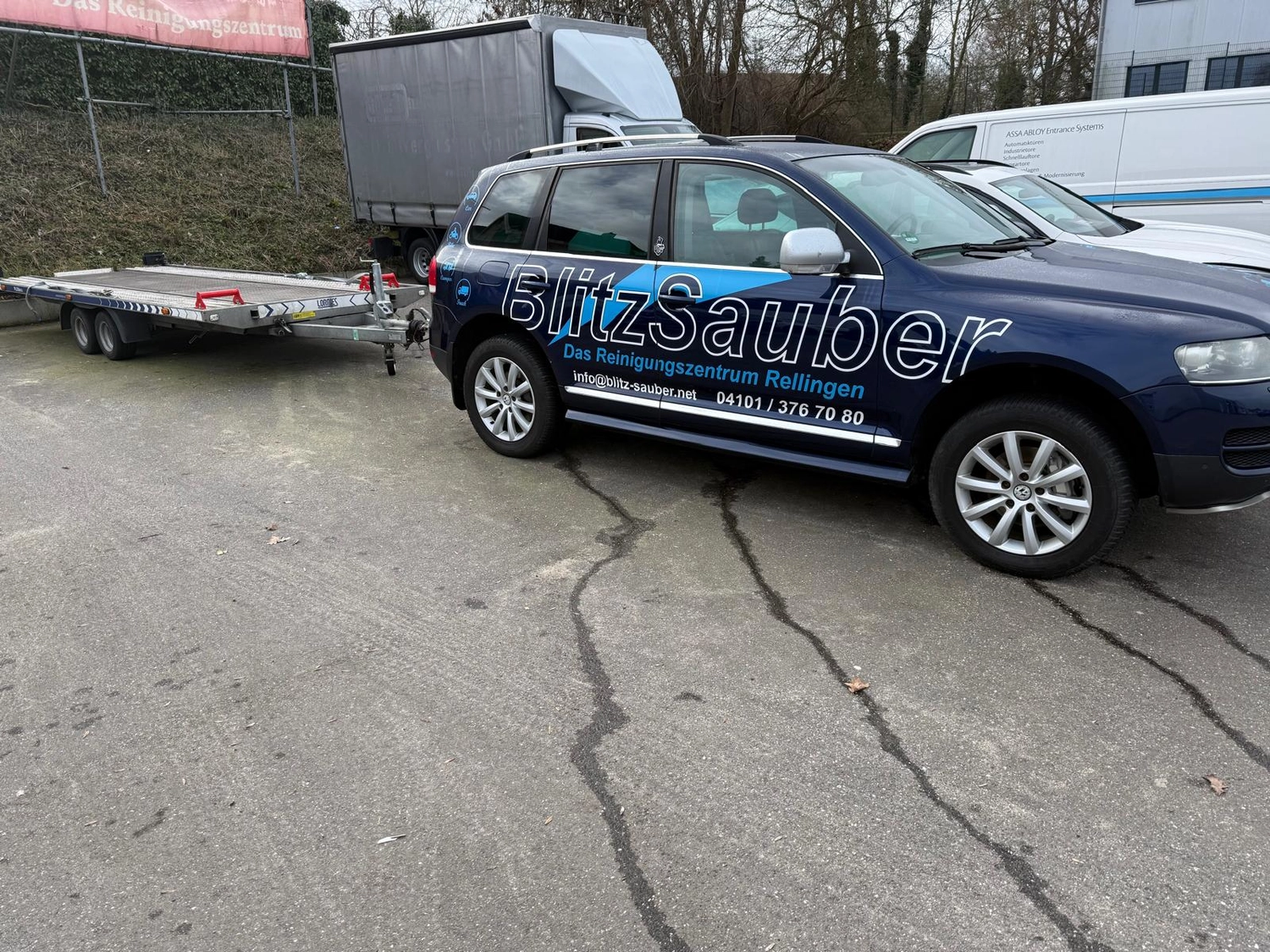 BlitzSauber das Reinigungszentrum Rellingen UG - Fahrzeugpflege - Dunkelblauer SUV mit BlitzSauber-Reinigungsdienst-Branding parkt auf Asphalt neben anderen Fahrzeugen